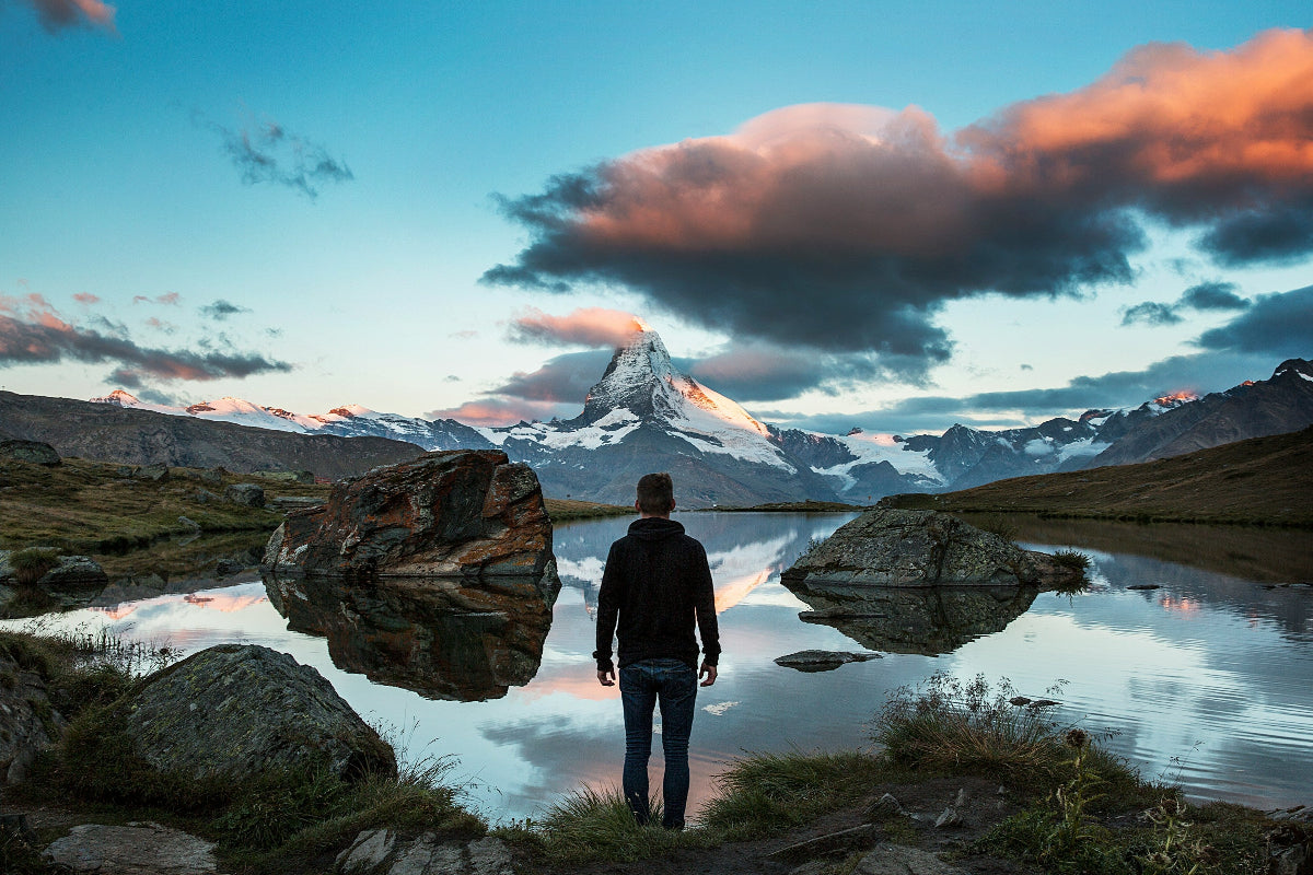 Man overlooking beautiful scenery of mountain with silhouette over a lake at dawn of new day as he has mastered life.